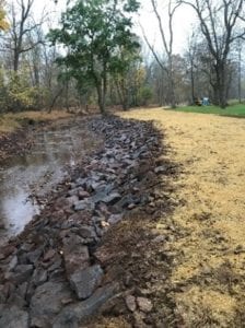 A photograph of rock lining the toe of a bank and erosion control blanket on the bank.